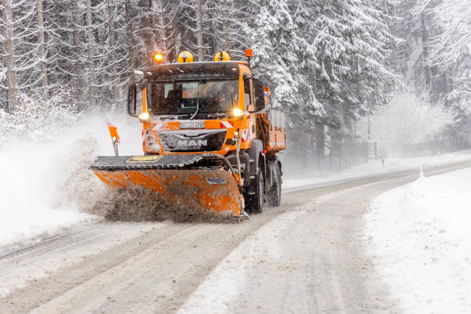 Räumfahrzeug mit Schneeschild räumt eine verschneite Straße – Winterdienst für Unternehmen und Hausverwaltungen